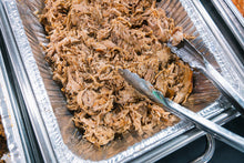 Top-down view of pulled pork in foil container, fully cooked and ready to serve