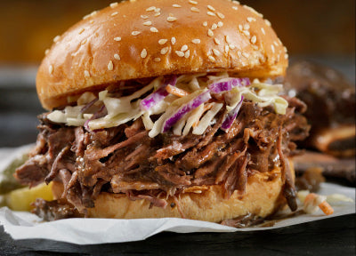 Side view of pulled pork sandwich on soft bun with visible texture and moisture