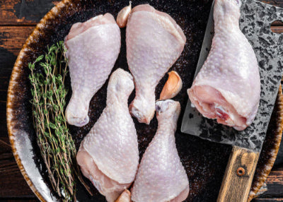 Raw pasture-raised chicken drumsticks on grill, ready to cook, top-down view
