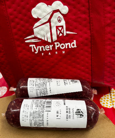 Two packages of meat with labels on a brown surface, Tyner Pond Farm logo in the background.