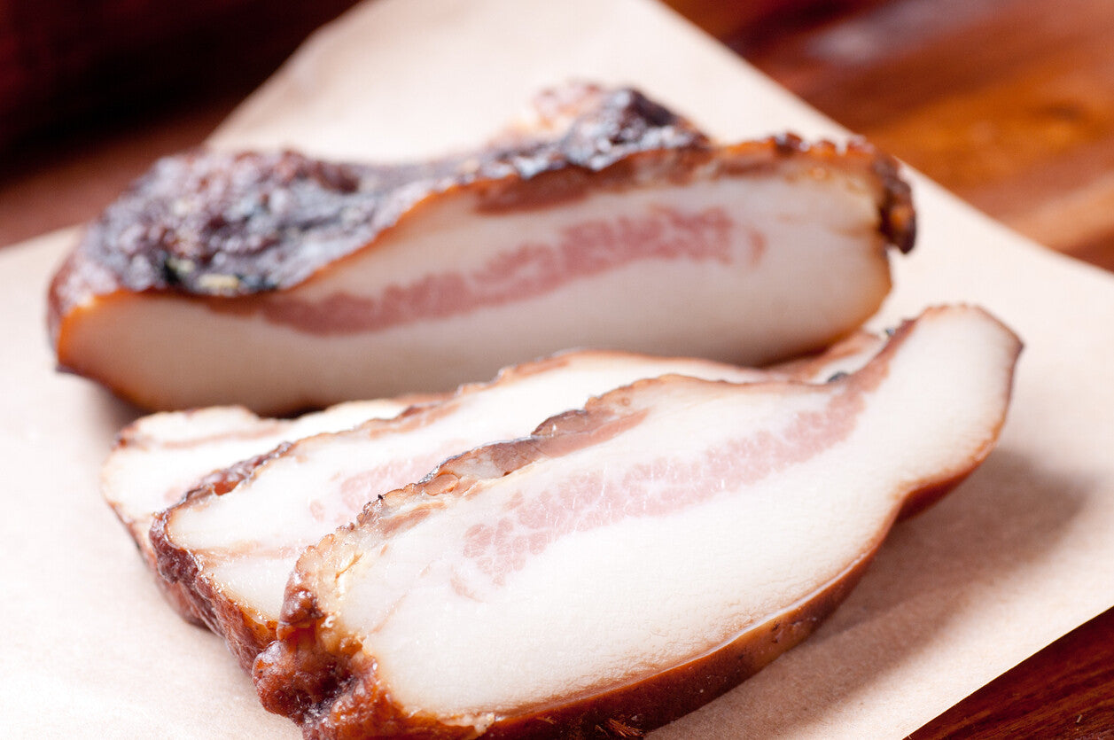 Raw pork jowl bacon (guanciale) on butcher paper, cured and ready to slice