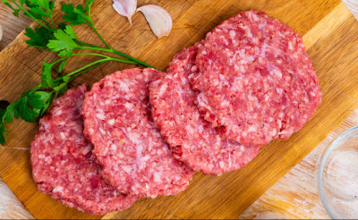Raw pork patties on wooden cutting board, 4 oz each, ready to cook