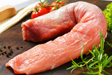 Raw pork tenderloin on wooden cutting board, trimmed and ready to cook