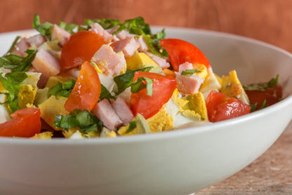 Tossed salad topped with diced ham, cheese, and tomato