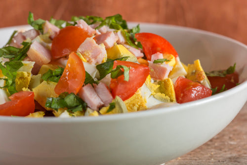 Tossed salad topped with diced ham, cheese, and tomato