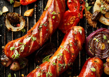 Santa Fe pork brats grilling with red chile peppers, browned and ready to serve