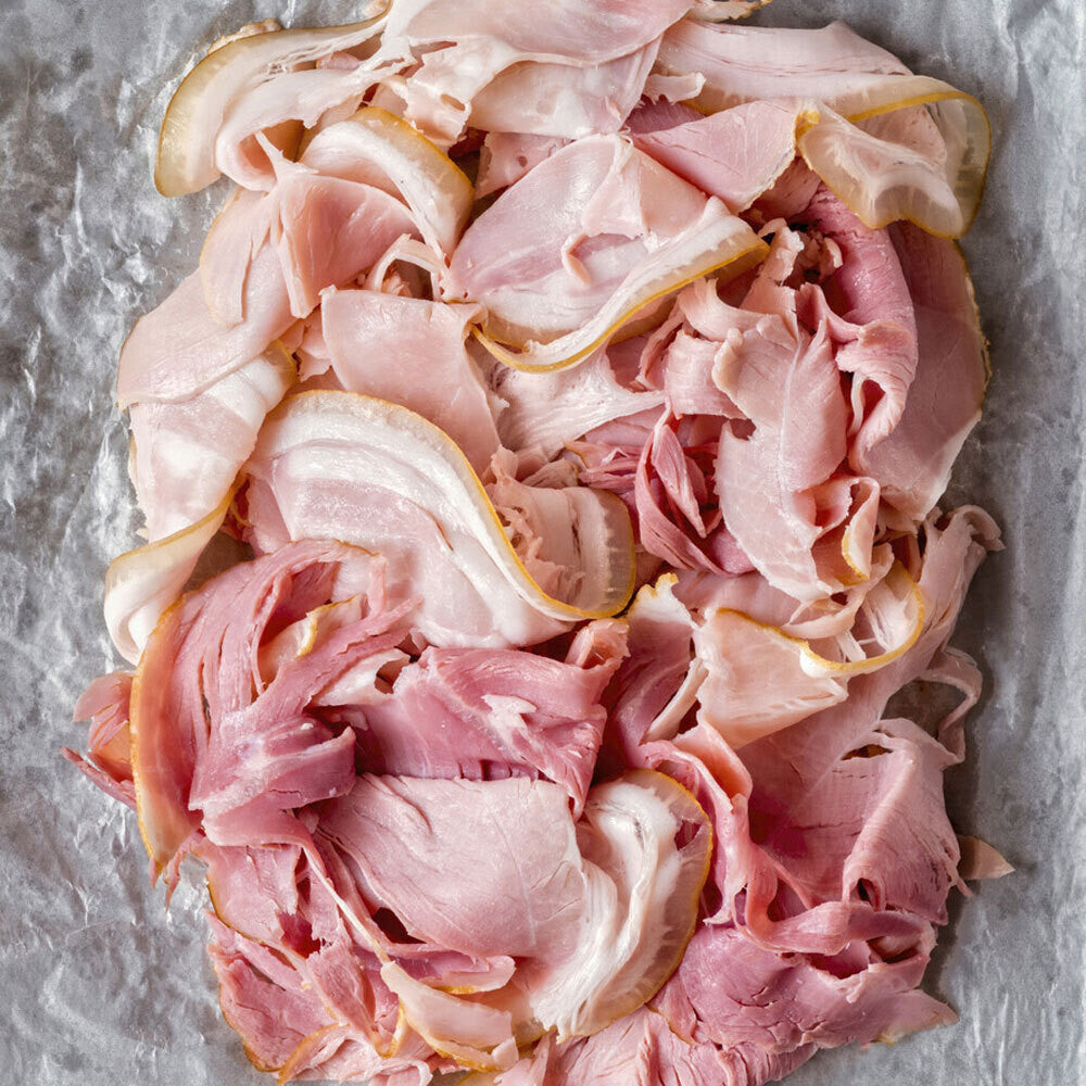 Top-down view of raw shaved ham slices, delicately folded and ready to serve