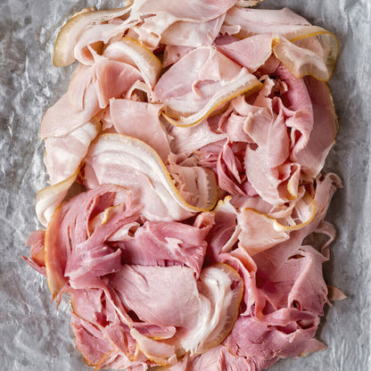 Top-down view of raw shaved ham slices, delicately folded and ready to serve