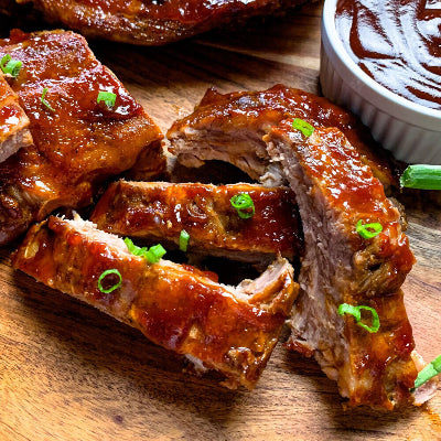 Cooked baby back ribs with dark caramelized crust, sliced and served