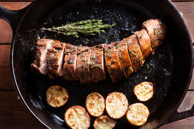 Top-down view of cooked pork tenderloin sliced in cast iron pan