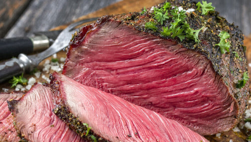 Sliced rare grassfed rump roast on cutting board, pasture-raised at Tyner Pond Farm