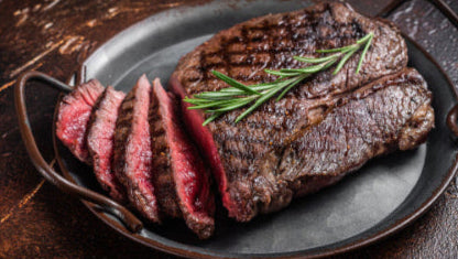Cooked grassfed top round steak sliced rare on platter, pasture-raised at Tyner Pond Farm