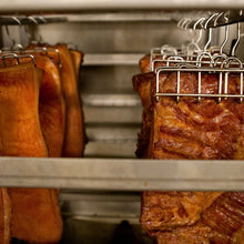 Smoking Goose pork bellies hanging in the smoker for Applewood Smoked Bacon