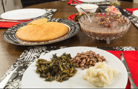 Southern meal with ham hock stew, collard greens, mashed potatoes, and cornbread