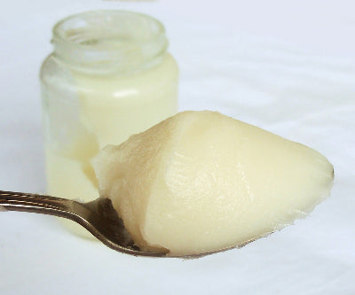 Kitchen tablespoon holding a rounded scoop of rendered pork lard