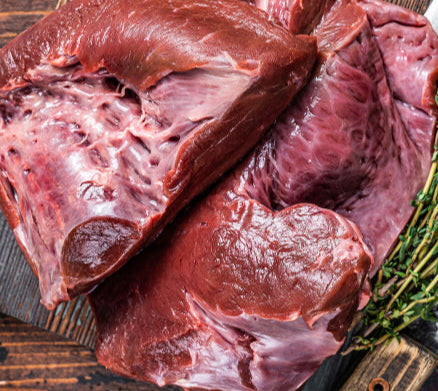 Top view of raw beef heart on wood surface, unprocessed organ cut from grass-finished cattle